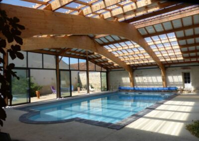 Piscine intérieure avec toiture vitrée laissant entrer une lumière naturelle agréable.